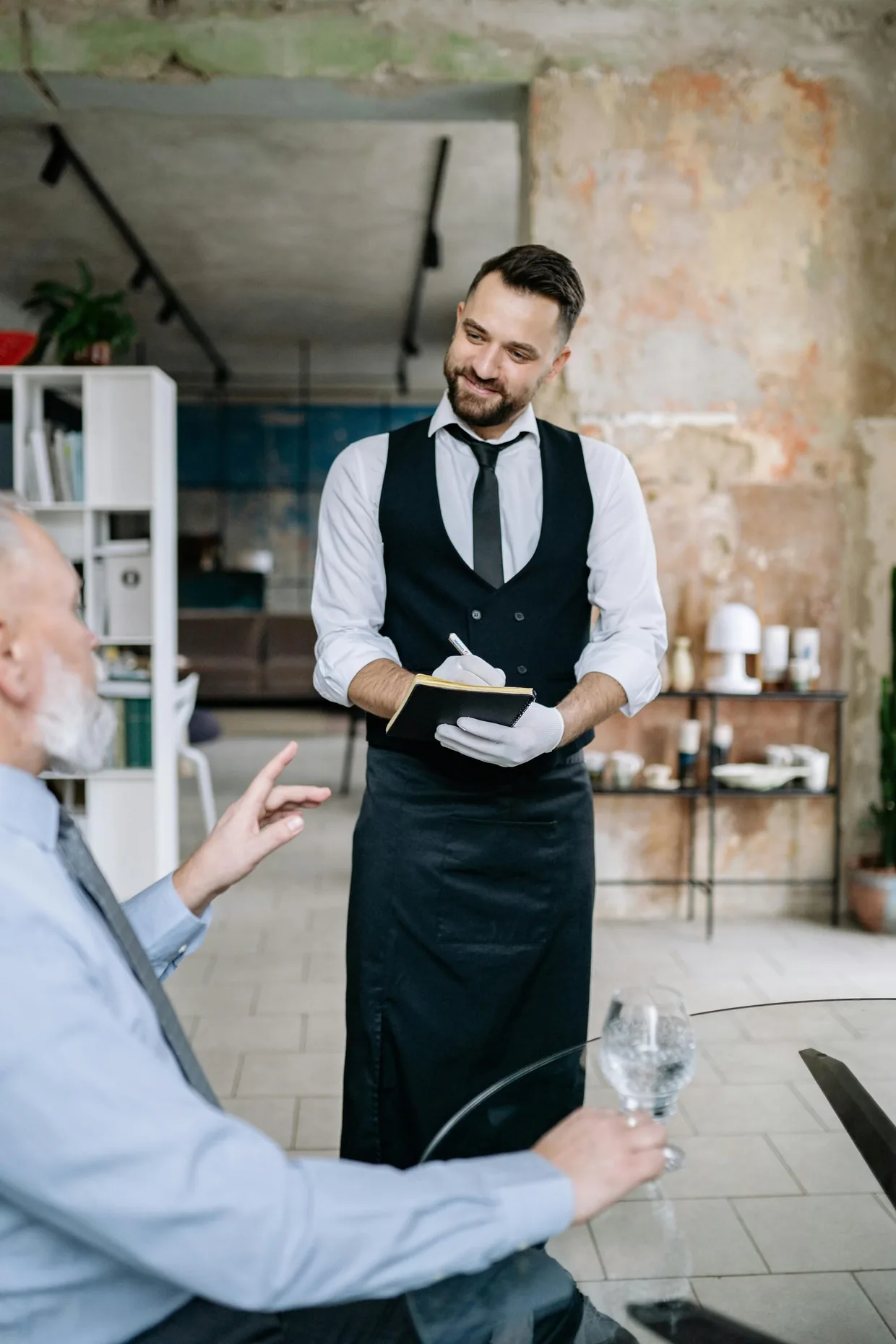 Waiter in a smart uniform shirt made from durable poly-viscose fabric, moving between tables in a restaurant